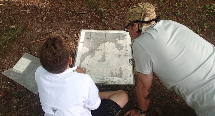 A parent and child examine a map on the ground.